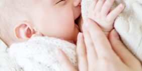 Mutter stillt ihr frischgeborenes Baby Eine Mutter stillt ihr frischgeborenes und lächelndes Baby.